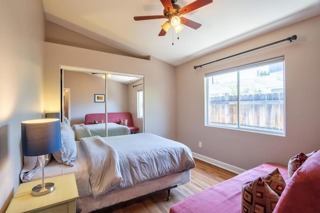 bedroom with ceiling fan, a closet, wood-type flooring, and vaulted ceiling