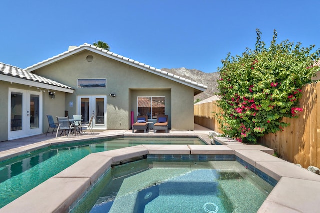 rear view of property with french doors, a patio area, and a swimming pool with hot tub