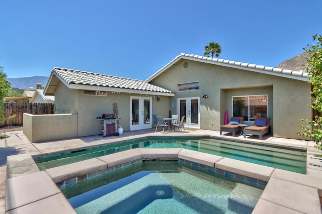 rear view of property featuring a mountain view, a pool with hot tub, a patio area, and french doors