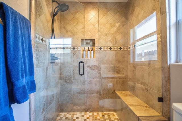 bathroom featuring a shower with door and toilet