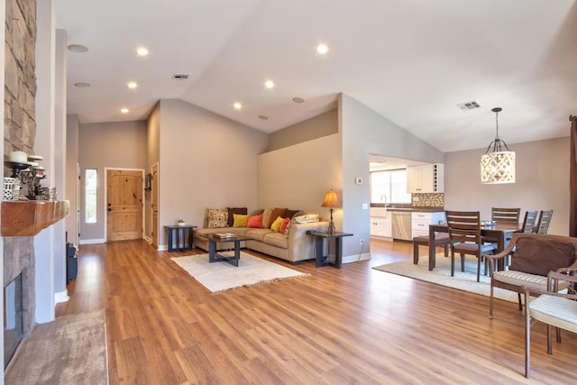 living room with light hardwood / wood-style floors, a fireplace, and high vaulted ceiling