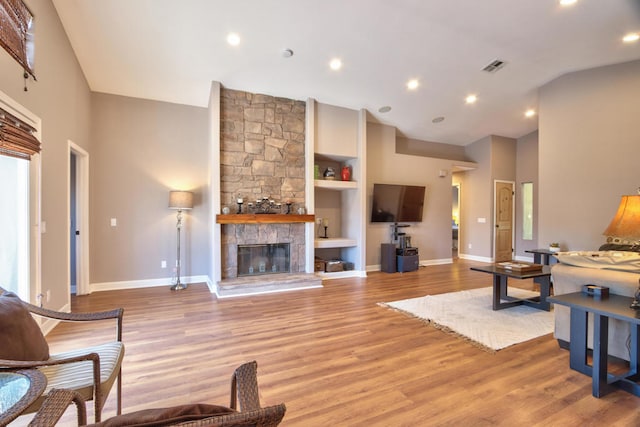 living room featuring a fireplace, light hardwood / wood-style flooring, and a high ceiling