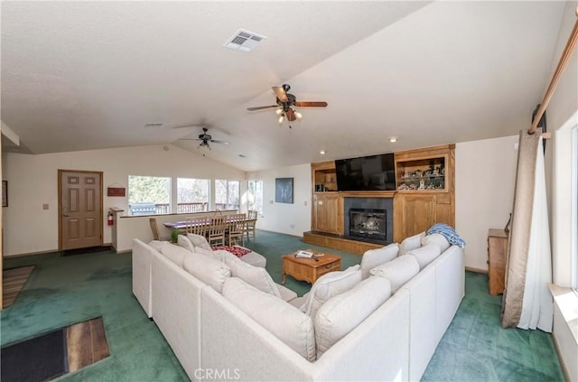 living room featuring ceiling fan, dark carpet, a fireplace, and vaulted ceiling