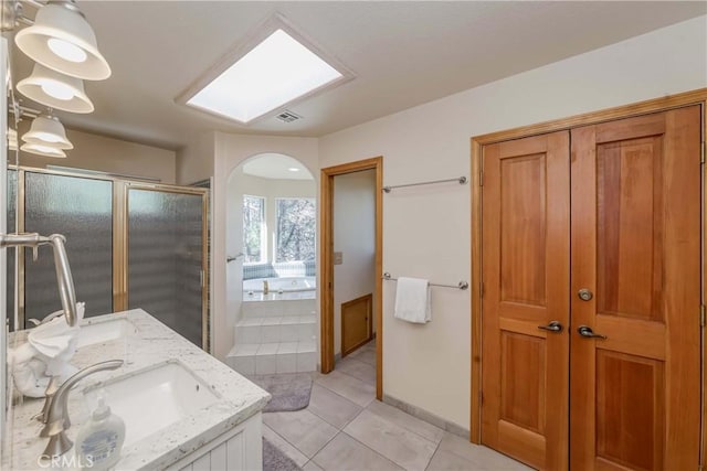 bathroom with tile patterned floors, a skylight, vanity, and independent shower and bath