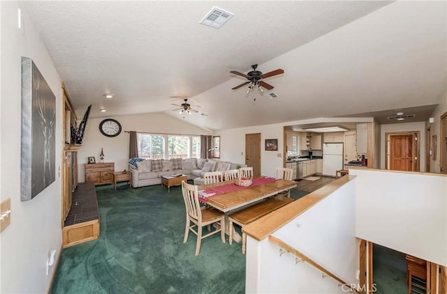 carpeted dining space with ceiling fan and vaulted ceiling