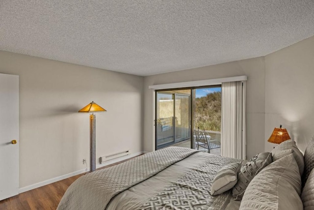 bedroom featuring access to exterior, hardwood / wood-style floors, a textured ceiling, and a baseboard heating unit