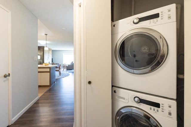 clothes washing area featuring dark hardwood / wood-style flooring and stacked washer and clothes dryer