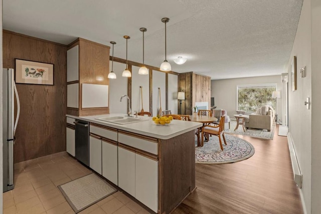 kitchen with stainless steel appliances, sink, decorative light fixtures, light hardwood / wood-style floors, and white cabinetry