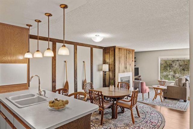 kitchen featuring a textured ceiling, a kitchen island with sink, sink, pendant lighting, and hardwood / wood-style flooring