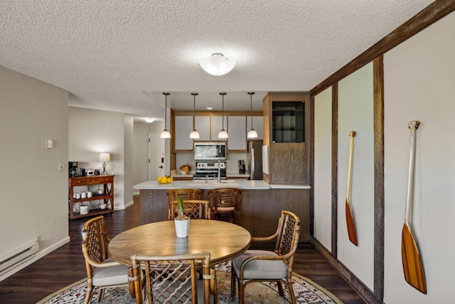 dining space featuring dark hardwood / wood-style flooring, a baseboard radiator, and a textured ceiling