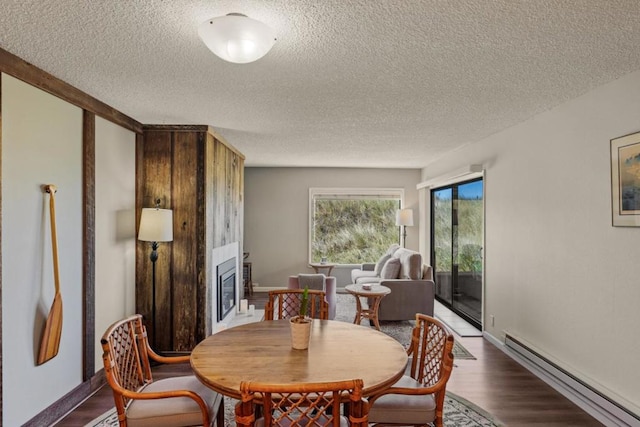 dining space featuring a textured ceiling, baseboard heating, and dark wood-type flooring