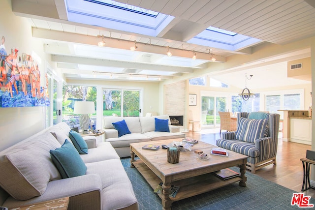 sunroom / solarium featuring vaulted ceiling with skylight and track lighting