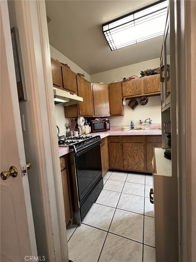 kitchen featuring black appliances, lofted ceiling, light tile patterned floors, and sink