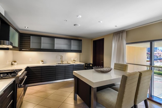 kitchen with sink, a center island, light tile floors, and range with gas stovetop