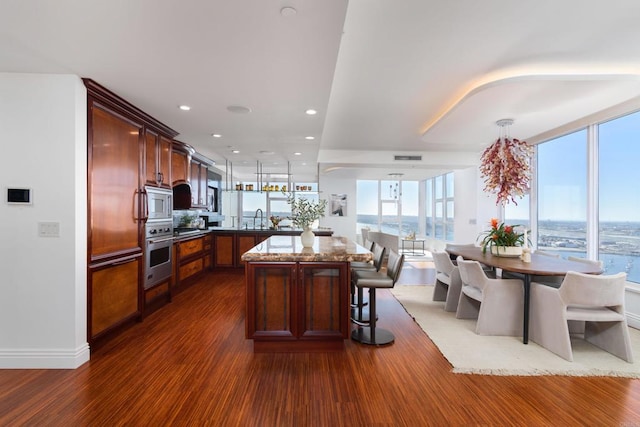 kitchen featuring appliances with stainless steel finishes, a center island, a breakfast bar, sink, and hardwood / wood-style flooring