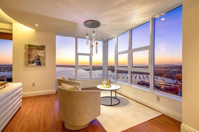 living area featuring a water view, an inviting chandelier, and hardwood / wood-style flooring