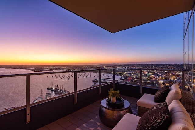 balcony at dusk featuring a water view