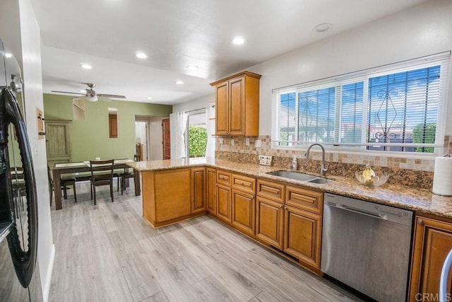 kitchen featuring kitchen peninsula, ceiling fan, light wood-type flooring, appliances with stainless steel finishes, and sink