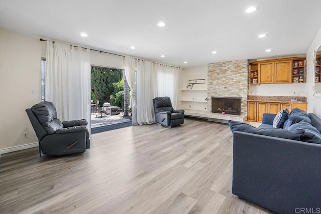 living room with built in shelves, a fireplace, and light wood-type flooring