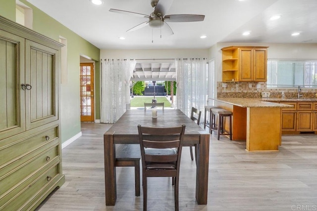 dining area with ceiling fan, light wood-type flooring, and sink