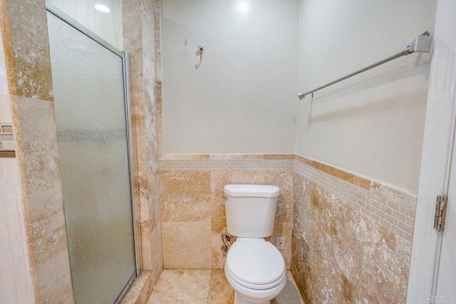 bathroom with tile flooring, tile walls, toilet, and a shower with door