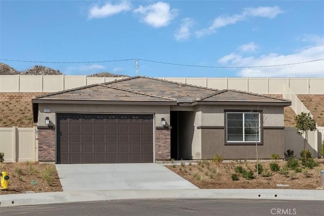 view of front of home with fence, a tile roof, stucco siding, a garage, and driveway