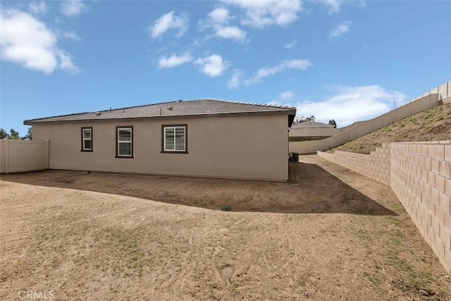 rear view of property with stucco siding and a fenced backyard