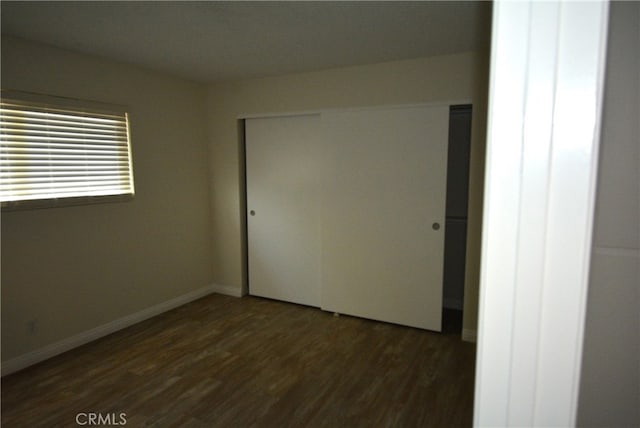 unfurnished bedroom with a closet and dark hardwood / wood-style floors