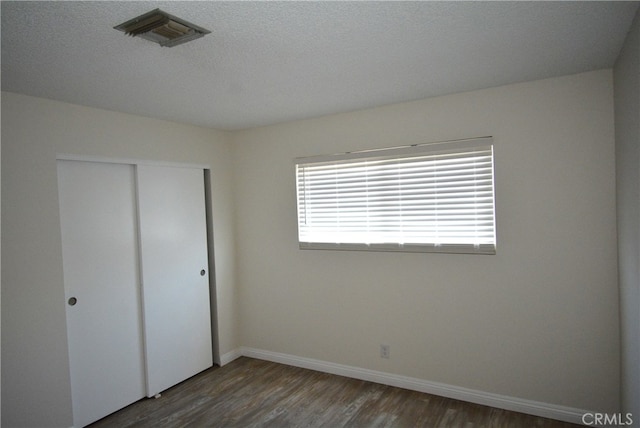 unfurnished bedroom featuring a closet and dark hardwood / wood-style floors