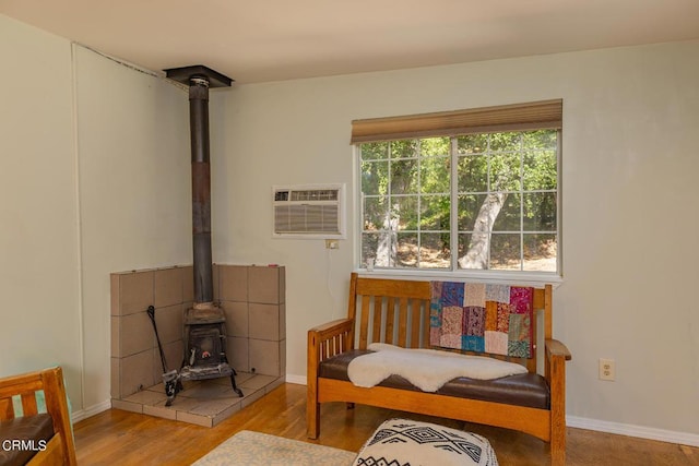 living area featuring light hardwood / wood-style floors, a wood stove, and a wall mounted AC