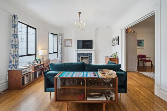 living room featuring an inviting chandelier, hardwood / wood-style floors, and a high end fireplace