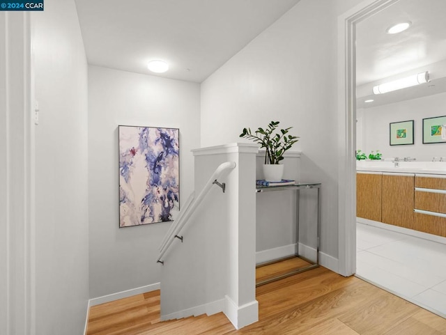 stairs with light hardwood / wood-style floors and sink