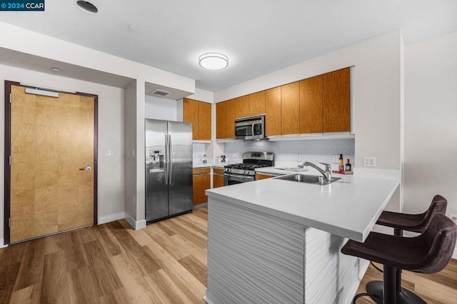 kitchen featuring a kitchen breakfast bar, light hardwood / wood-style flooring, and stainless steel appliances