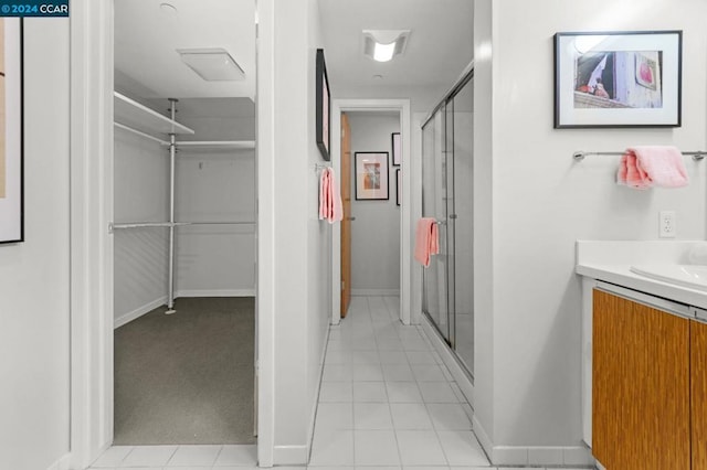 bathroom featuring a shower with shower door, vanity, and tile flooring