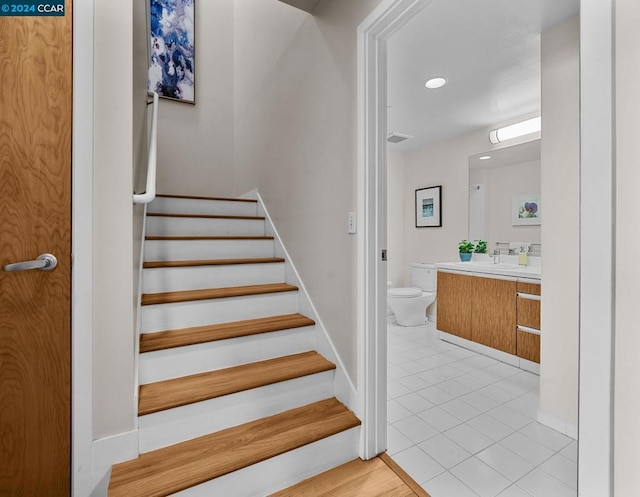 staircase featuring sink and light wood-type flooring