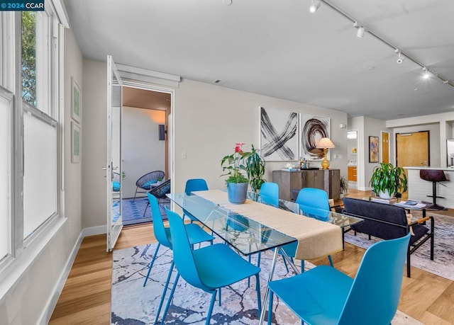 dining area featuring rail lighting and light hardwood / wood-style flooring