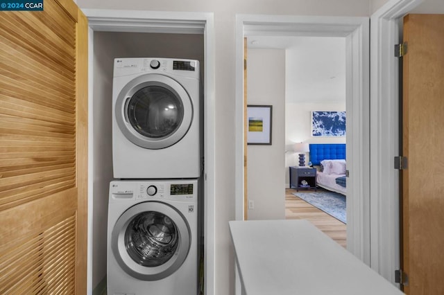 clothes washing area with stacked washer / drying machine and hardwood / wood-style flooring