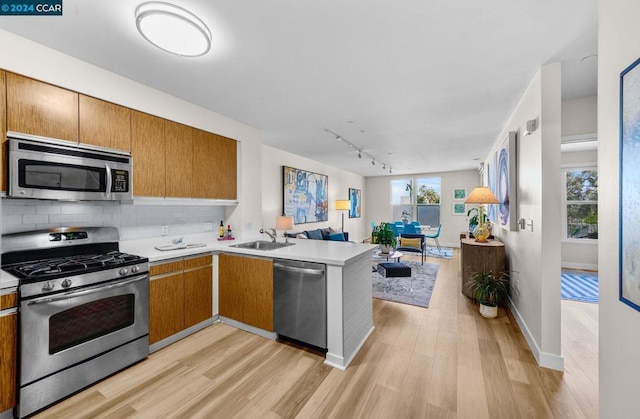 kitchen featuring plenty of natural light, stainless steel appliances, track lighting, and light wood-type flooring