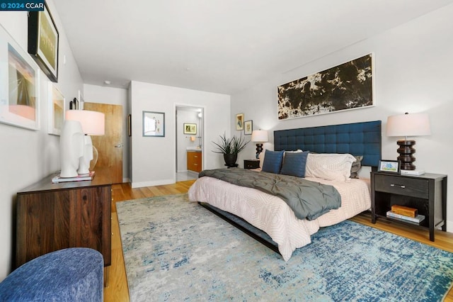 bedroom with hardwood / wood-style floors and connected bathroom