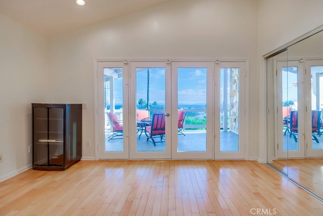 doorway to outside featuring light hardwood / wood-style flooring and vaulted ceiling