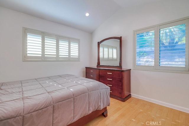 bedroom featuring multiple windows, lofted ceiling, and light wood-type flooring