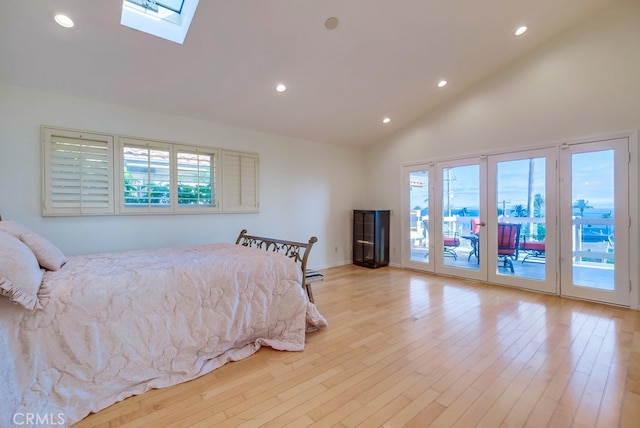 bedroom featuring light hardwood / wood-style flooring, access to outside, a skylight, and high vaulted ceiling