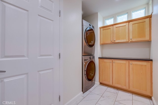 washroom with stacked washer / drying machine and cabinets