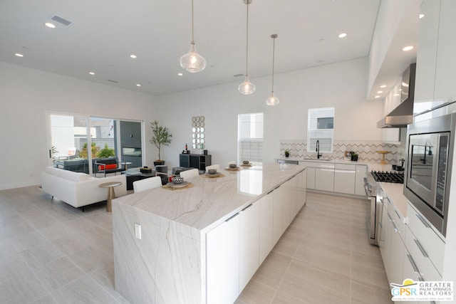 kitchen with backsplash, hanging light fixtures, appliances with stainless steel finishes, a kitchen island, and white cabinetry