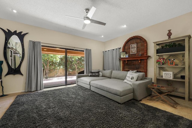 living room featuring ceiling fan and a textured ceiling