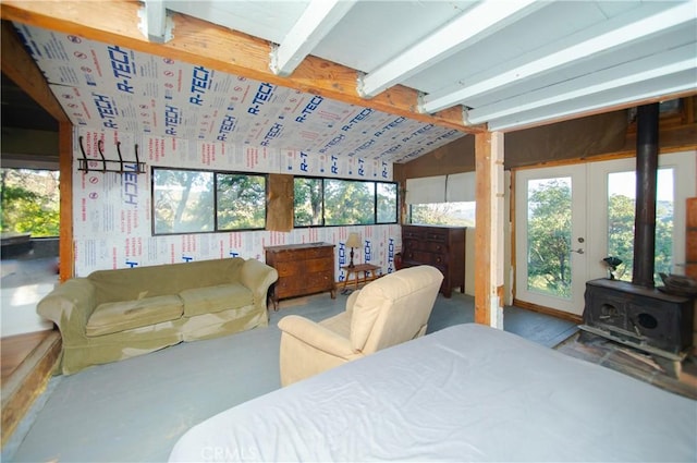 bedroom featuring access to outside, vaulted ceiling, multiple windows, and a wood stove