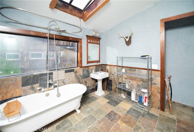 bathroom with sink, a washtub, tile walls, and a skylight