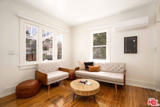 sitting room featuring hardwood / wood-style flooring, a wealth of natural light, and an AC wall unit