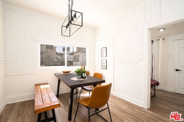 dining room with hardwood / wood-style flooring and brick wall