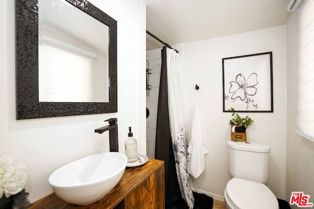 bathroom with toilet, curtained shower, and sink